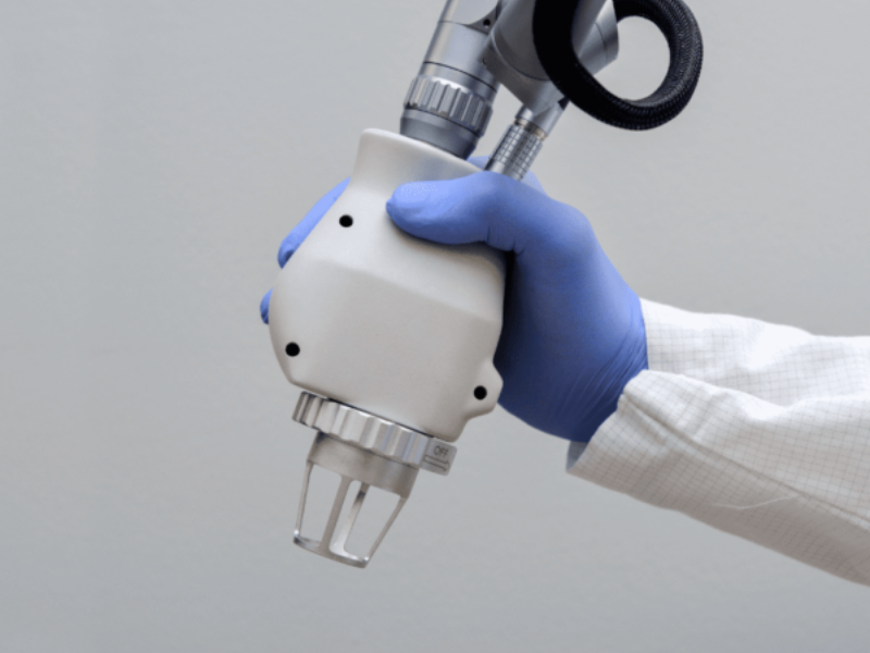 A gloved hand holding a professional laser treatment handpiece
