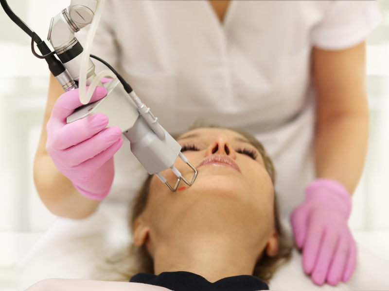 Professional administering laser skin therapy for facial rejuvenation