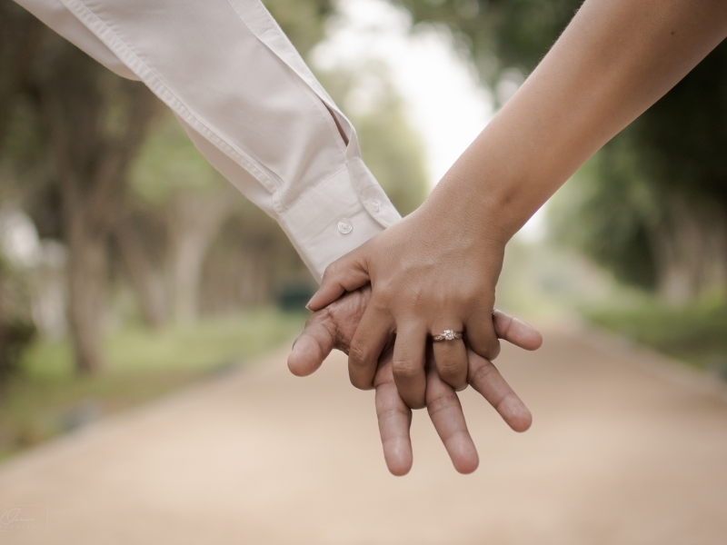 Close-up of a couple holding hands with an engagement ring