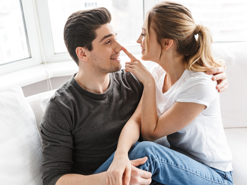 Smiling woman playfully touching her partner’s nose while cuddling