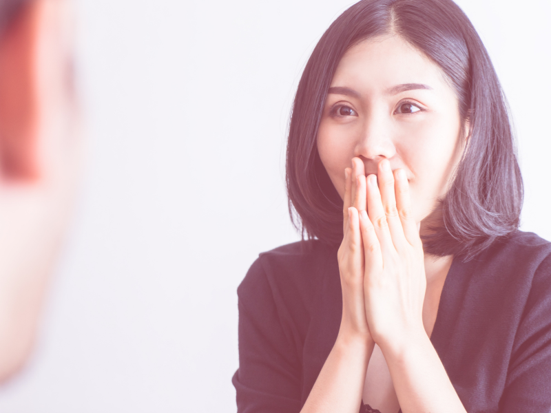 Woman covering mouth with hands while reacting to conversation