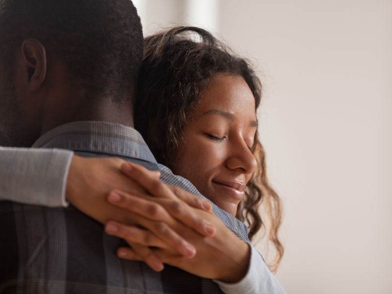 A woman smiling while hugging a man, showing deep affection