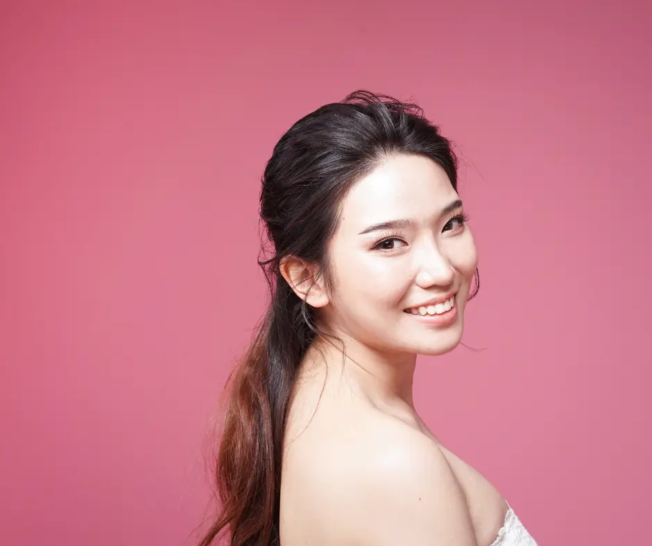 Young woman smiling against a pink background with a radiant glow