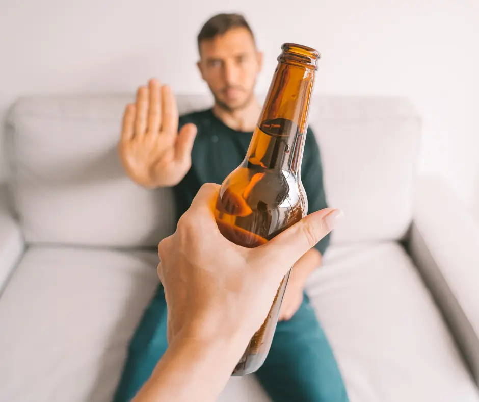 A man rejecting an offered beer bottle, symbolizing a commitment to an alcohol-free lifestyle