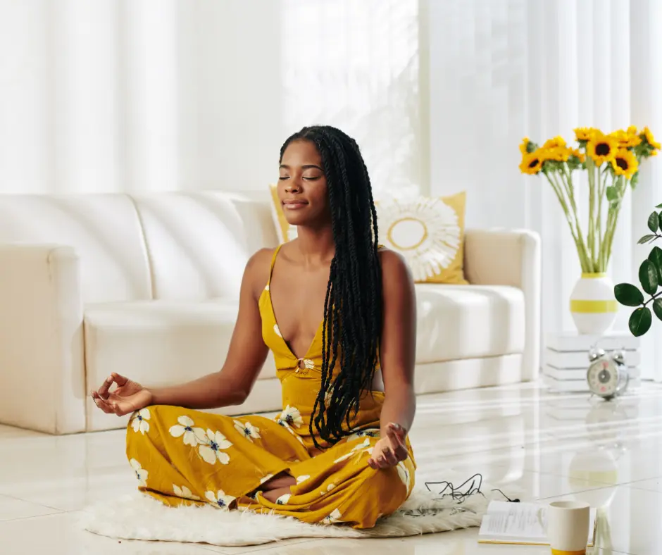 A woman in a yellow dress meditating peacefully in a bright and cozy living space