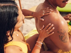 Woman applying Sun Bum sunscreen on a man's shoulder