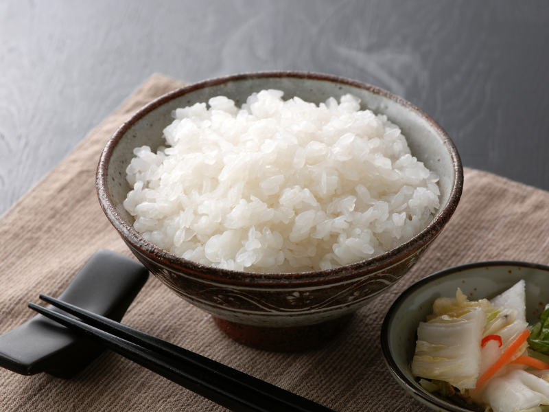 A bowl of fluffy white rice with chopsticks beside it