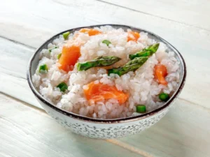 A bowl of sushi rice topped with salmon and asparagus