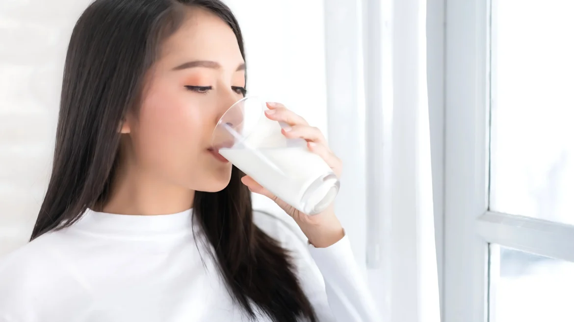 A woman drinking a beverage infused with glutathione and collagen.