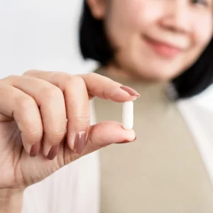 a woman holding a pill with her left hand